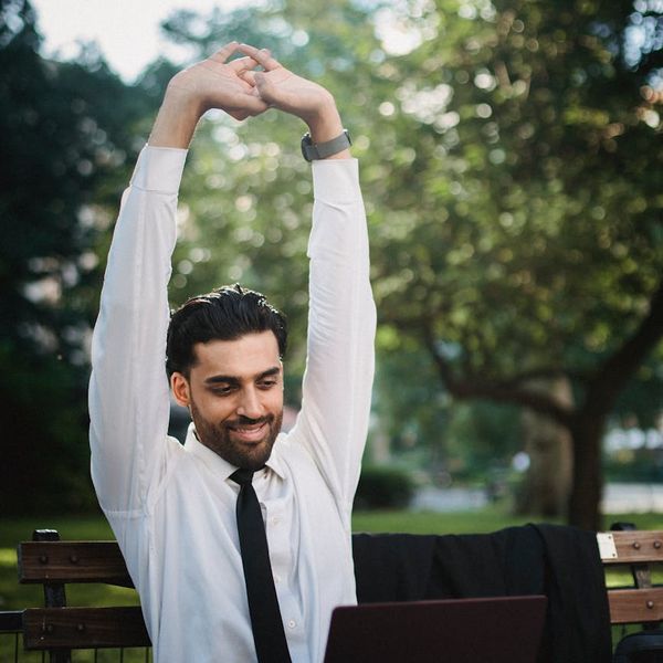 Person smiling and stretching outdoors in a natural setting.